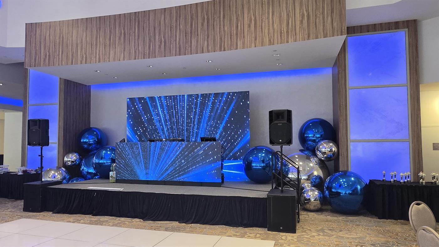 Ballroom stage with an LED video wall, LED DJ booth and white speakers either side
