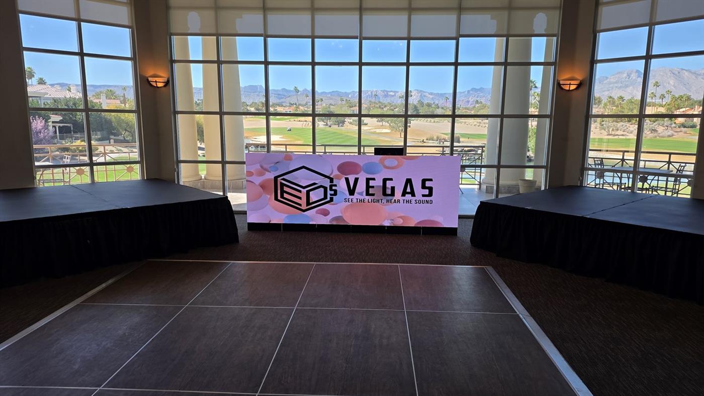 LED DJ booth with LEDs VEGAS branding between two stage decks, golf course beyond